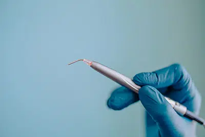 Dr. Kym holding a laser used for more efficient dental procedures at Prime Dental