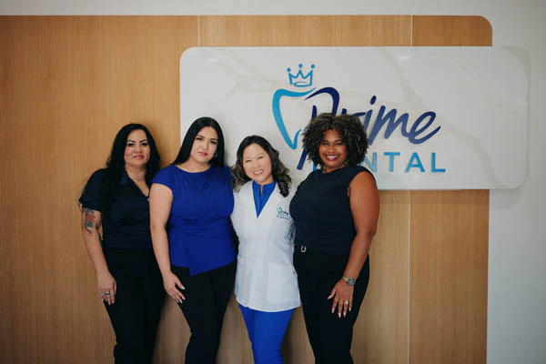 Prime Dental front desk team by office sign